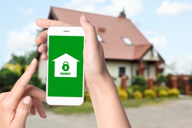 Image of Home security system. Woman with smartphone near her house outdoors, closeup