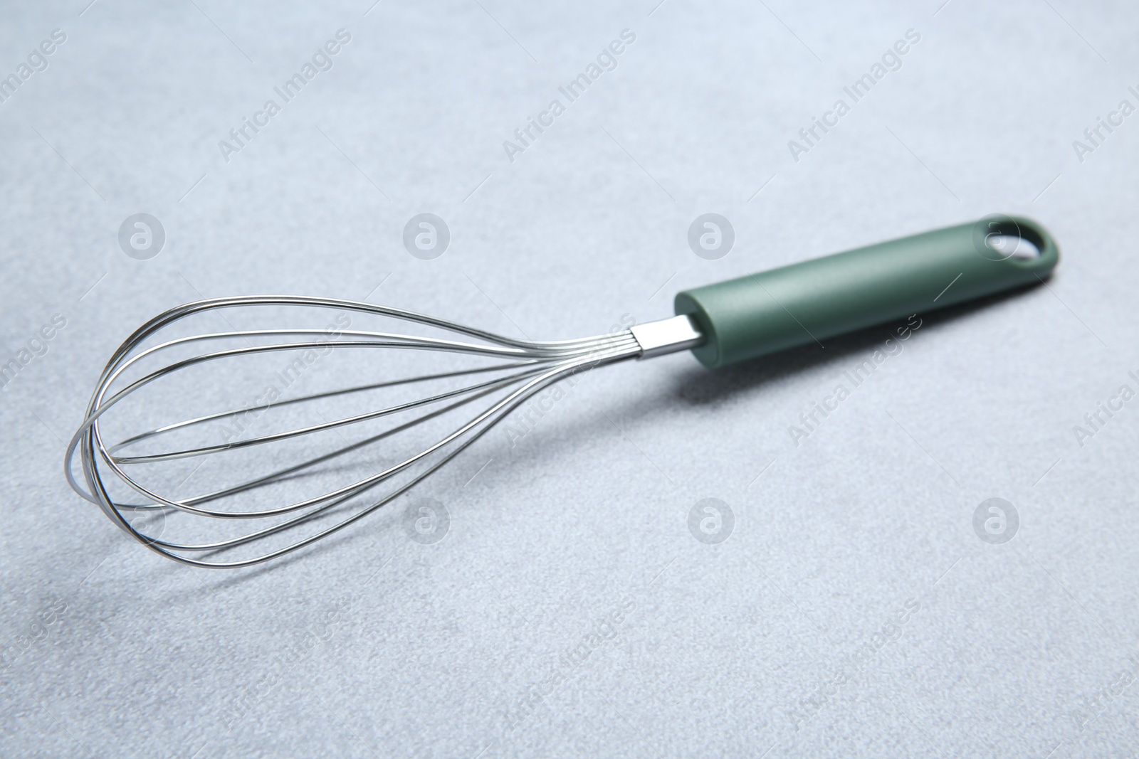 Photo of Metal whisk on gray table. Kitchen tool