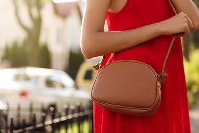 Photo of Woman with stylish bag in red dress outdoors, closeup. Space for text