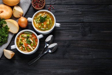 Photo of Bowls of tasty turnip soup and ingredients on dark wooden table, flat lay. Space for text