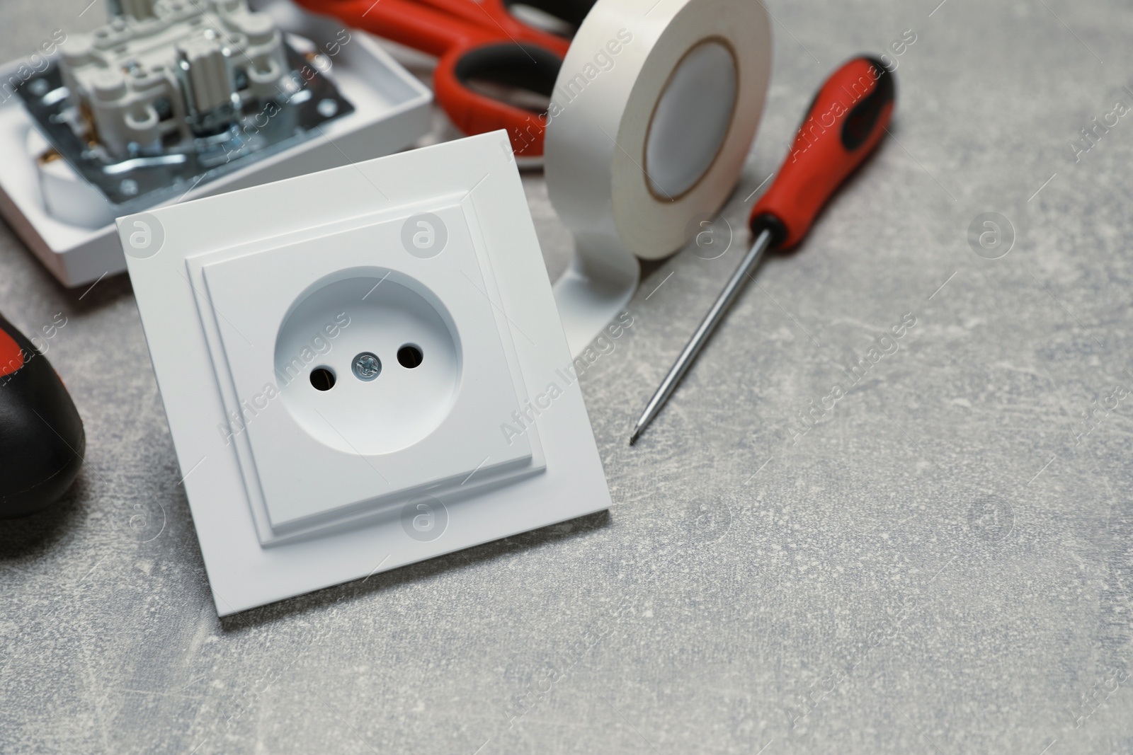 Photo of Power socket and electrician's tools on grey table. Space for text