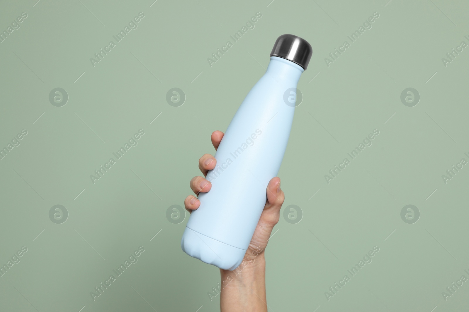 Photo of Woman holding thermo bottle on green background, closeup