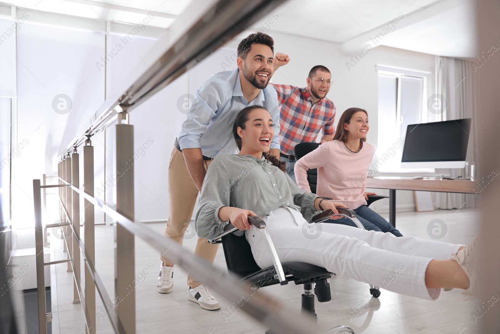 Photo of Happy office employees riding chairs at workplace