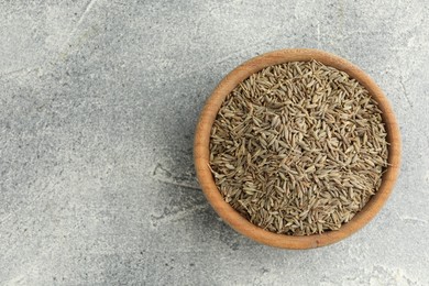 Photo of Bowl of caraway seeds on grey table, top view. Space for text