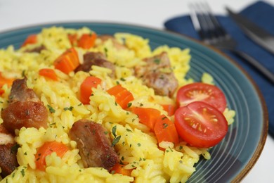 Delicious pilaf with meat and tomatoes on plate, closeup