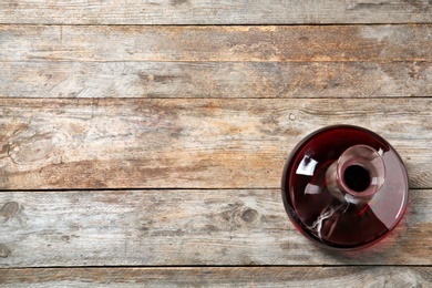 Decanter with red wine on wooden background, top view