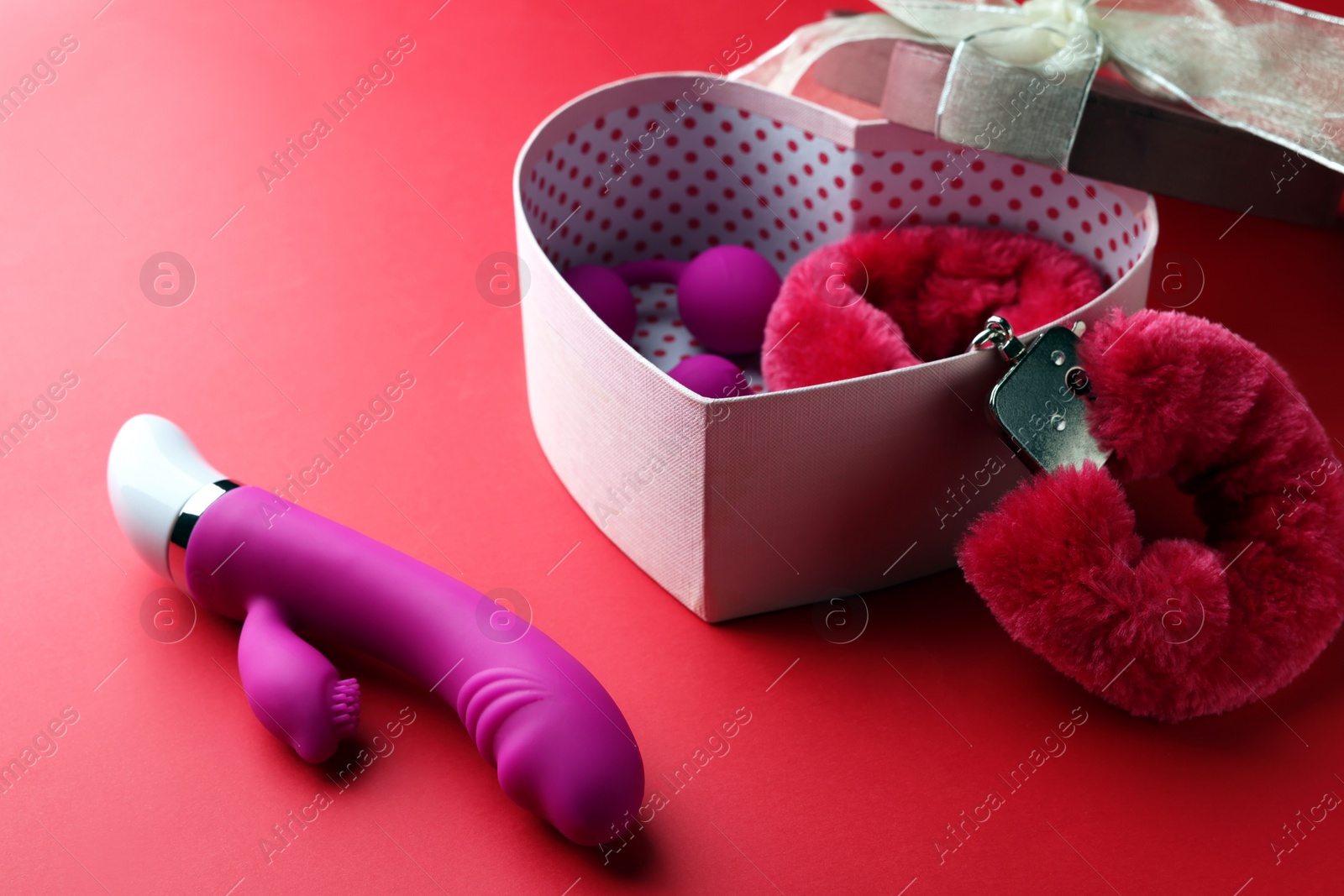 Photo of Gift box with different sex toys on red background