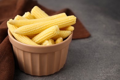 Photo of Tasty fresh yellow baby corns in bowl on brown table, closeup. Space for text