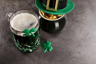 St. Patrick's day celebration. Green beer, leprechaun hat, pot of gold and decorative clover leaves on grey table. Space for text