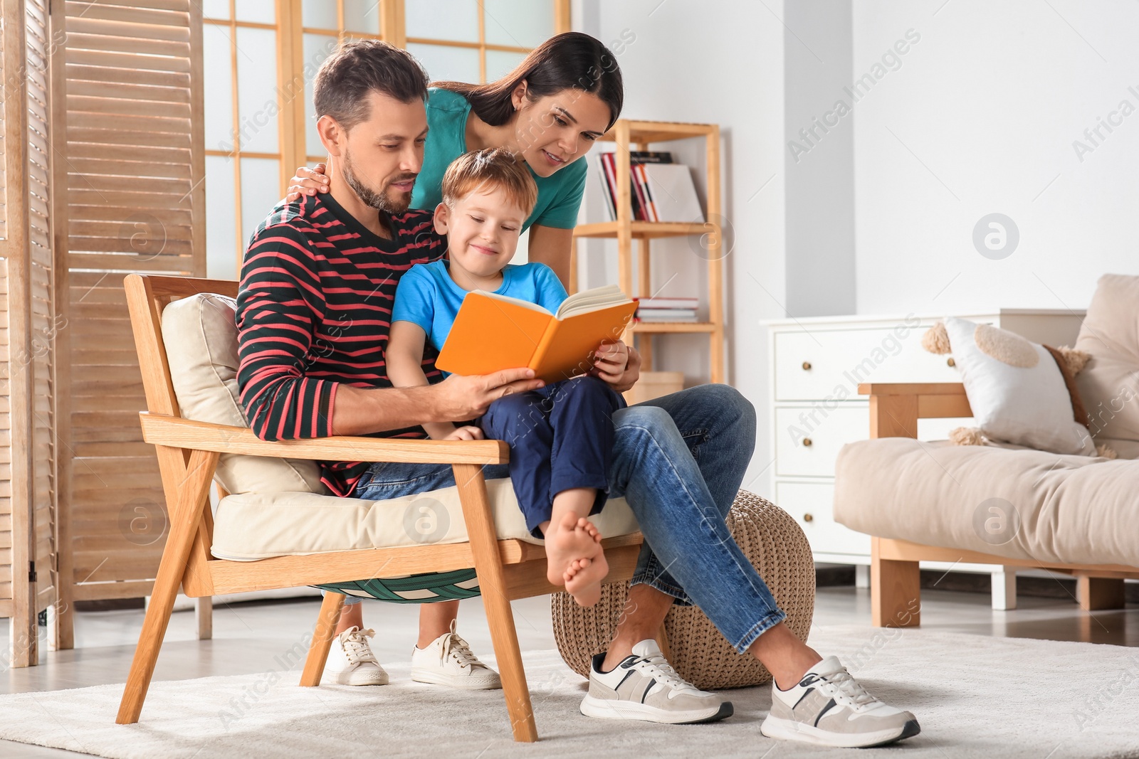 Photo of Happy family reading book together in living room at home