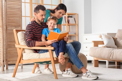 Photo of Happy family reading book together in living room at home