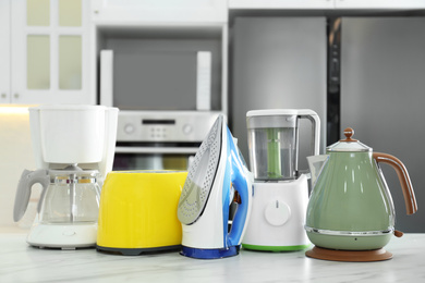 Photo of Set of modern home appliances on white marble table in kitchen