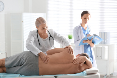 Photo of Female orthopedist examining patient's back in clinic