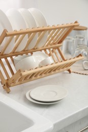 Drying rack with clean dishes on light marble countertop in kitchen