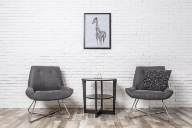 Photo of Room interior with modern chairs and table near white brick wall