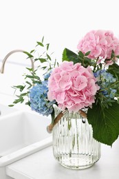 Photo of Beautiful hortensia flowers in vase on kitchen counter