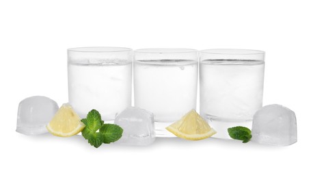 Photo of Shot glasses of vodka with lemon slices, mint and ice on white background