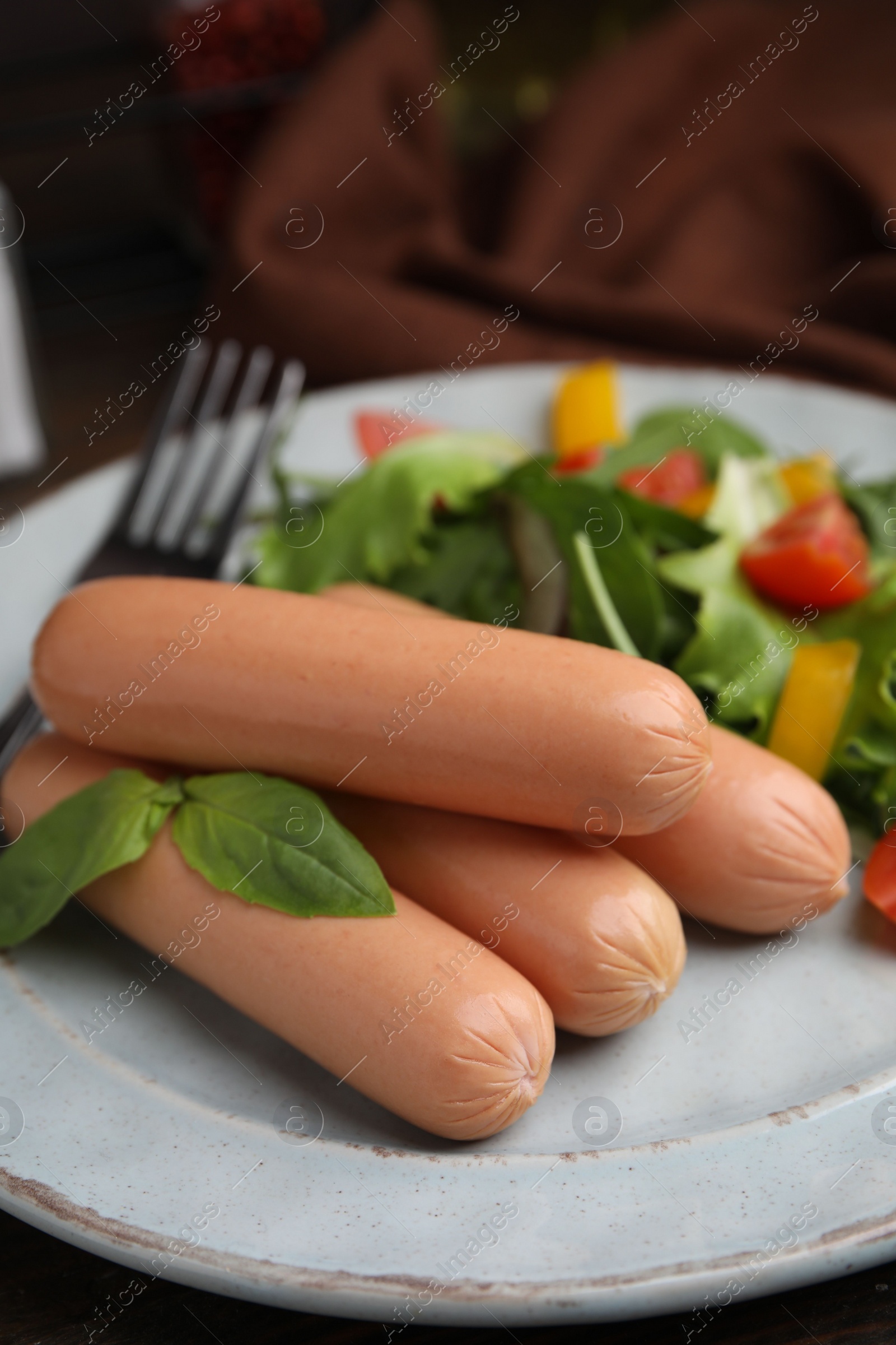 Photo of Delicious boiled sausages with salad on table, closeup