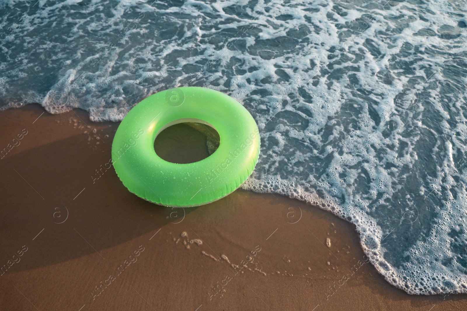 Photo of Green inflatable ring on sandy beach near sea, space for text