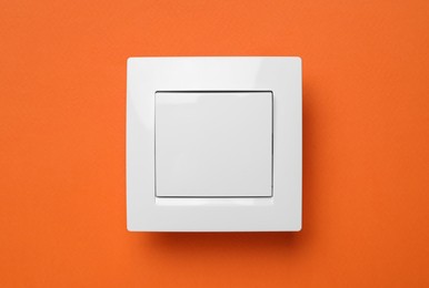 Photo of White plastic light switch on orange background