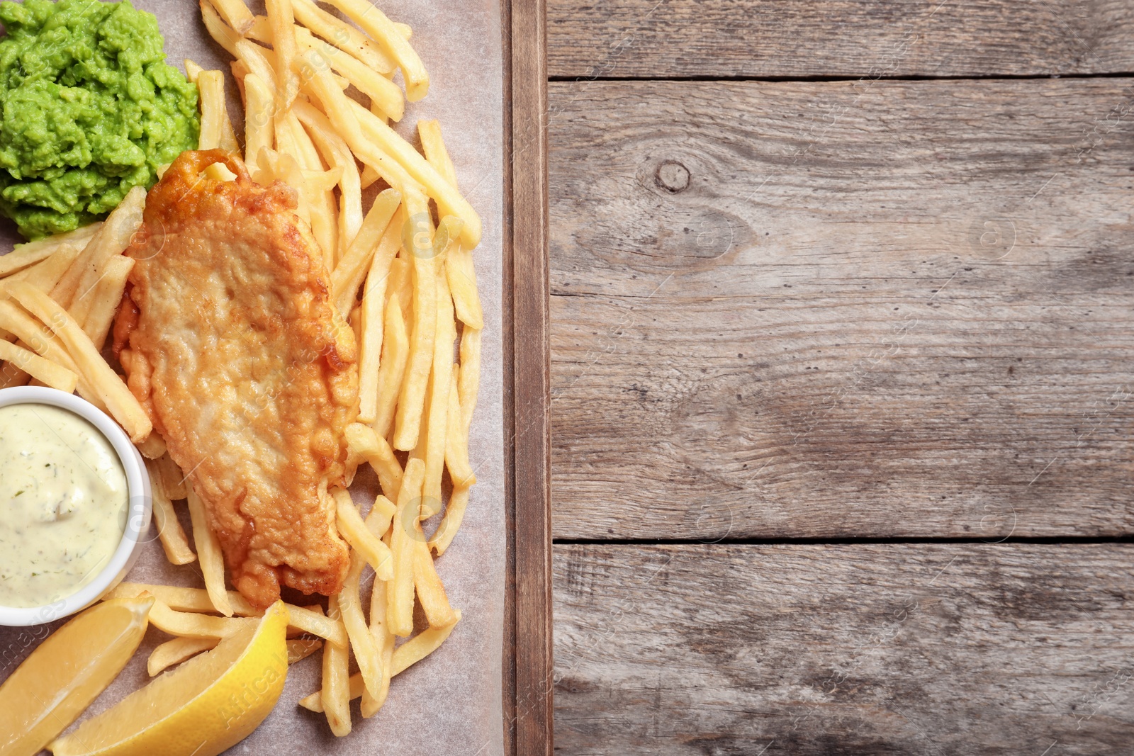 Photo of British traditional fish and potato chips on wooden background, top view with space for text