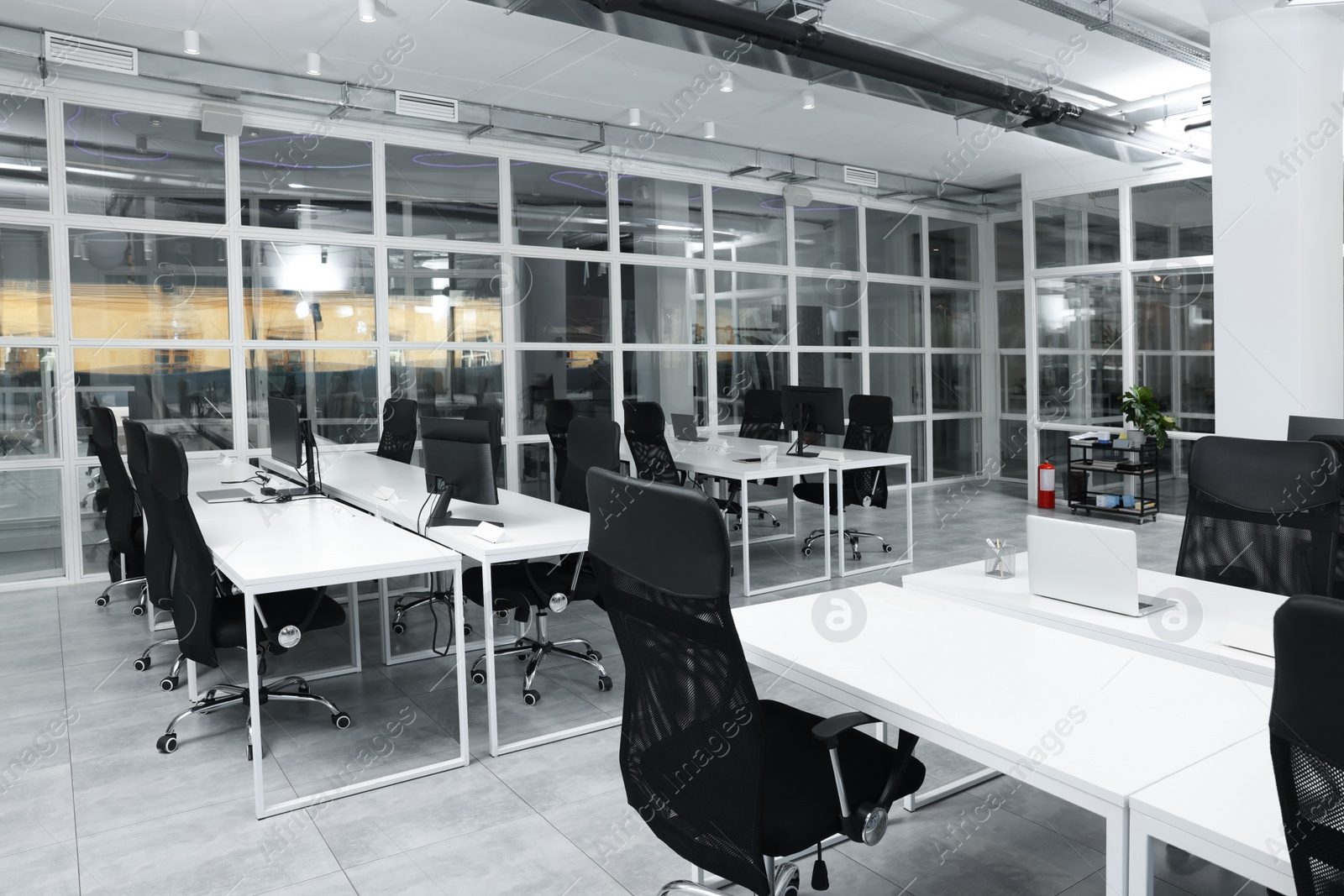 Photo of Stylish interior of open plan office. Workspace with computers, tables and chairs