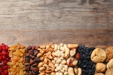 Photo of Different dried fruits and nuts on wooden background, top view. Space for text