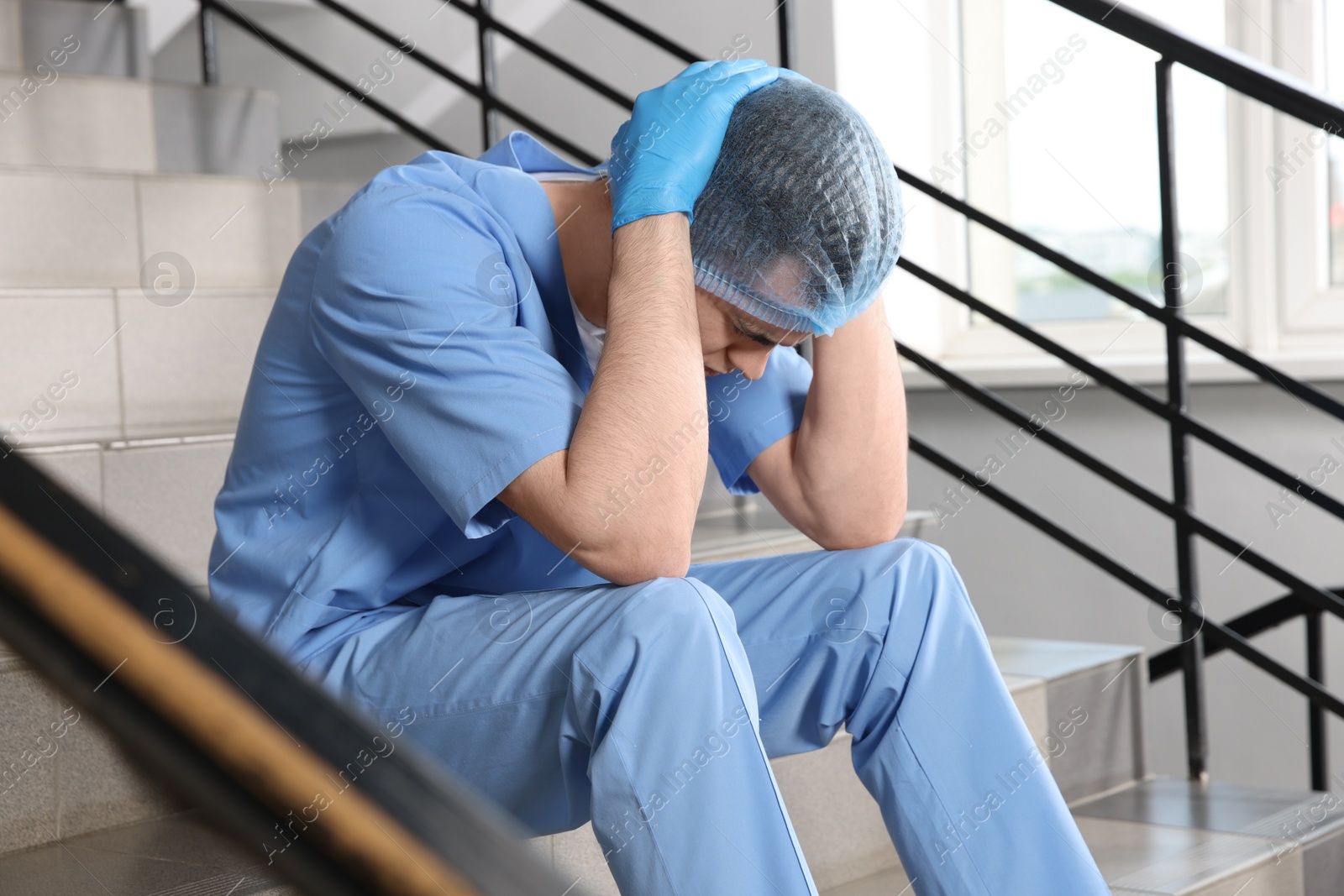 Photo of Exhausted doctor sitting on stairs in hospital