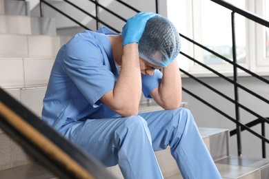 Exhausted doctor sitting on stairs in hospital