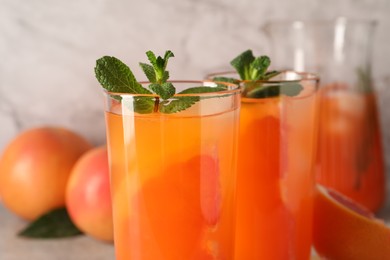 Photo of Tasty freshly made grapefruit juice with mint on table, closeup