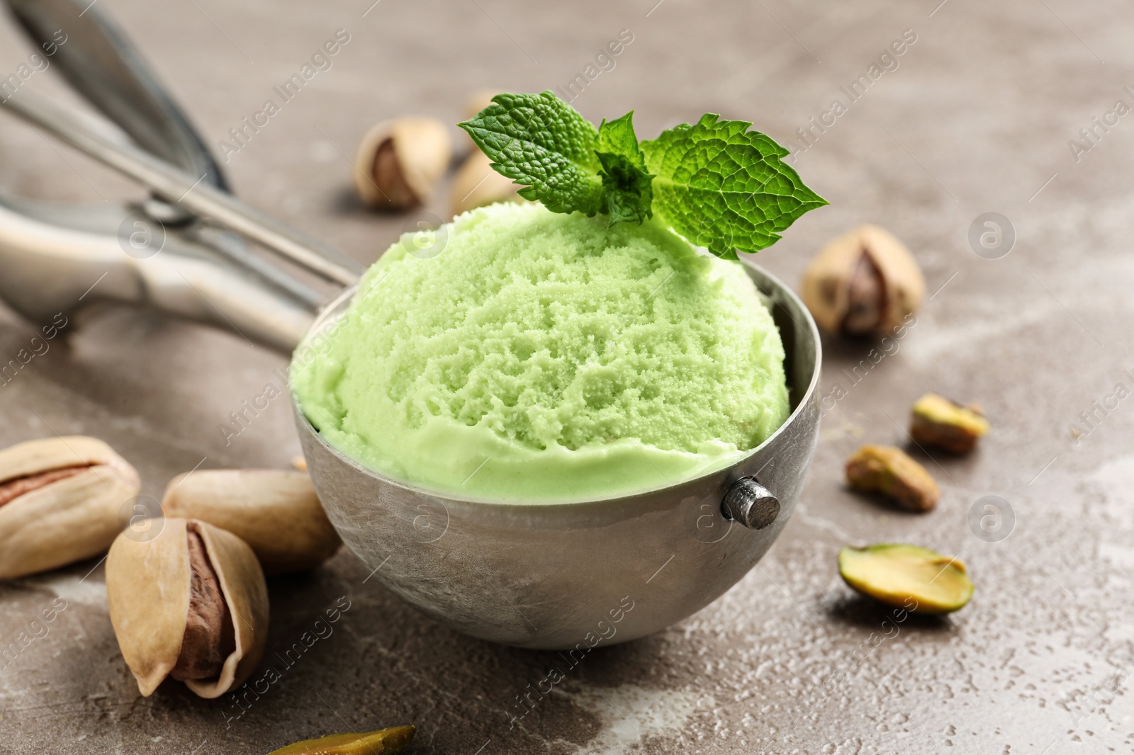 Photo of Scoop with tasty pistachio ice cream on grey table, closeup view