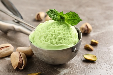Scoop with tasty pistachio ice cream on grey table, closeup view