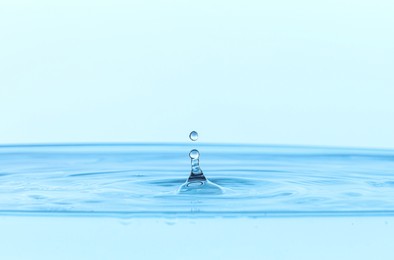 Photo of Splash of clear water with drop on light blue background, closeup