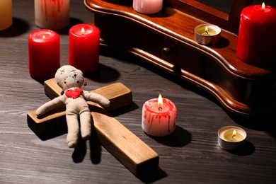 Voodoo doll with pins in heart and ceremonial items on wooden table