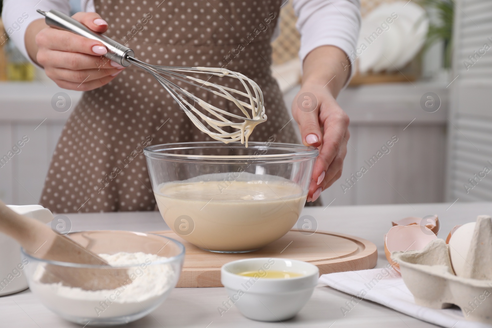 Photo of Woman making dough with whisk in bowl at table, closeup