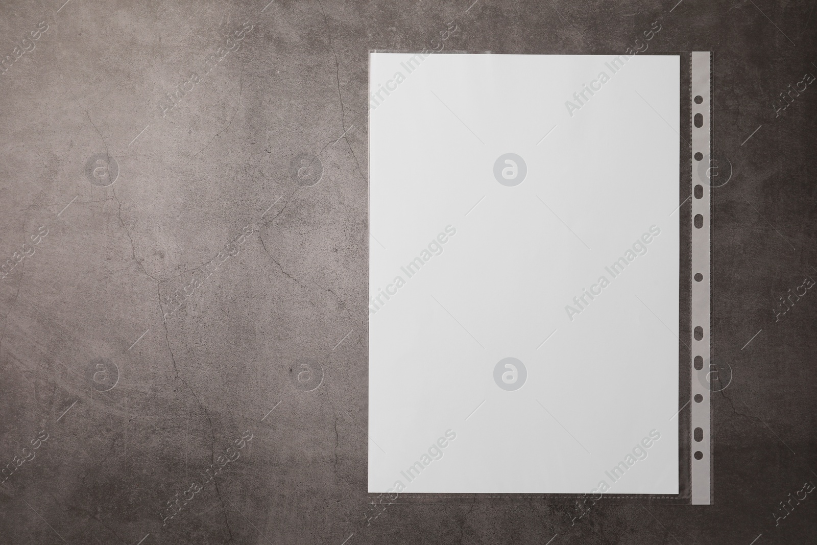 Photo of Punched pocket with paper sheet on grey table, top view. Space for text