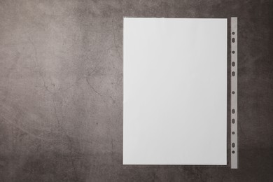 Punched pocket with paper sheet on grey table, top view. Space for text