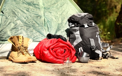 Rolled sleeping bag and other camping gear outdoors on sunny day