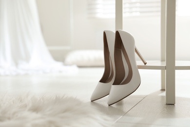 Pair of white wedding high heel shoes indoors