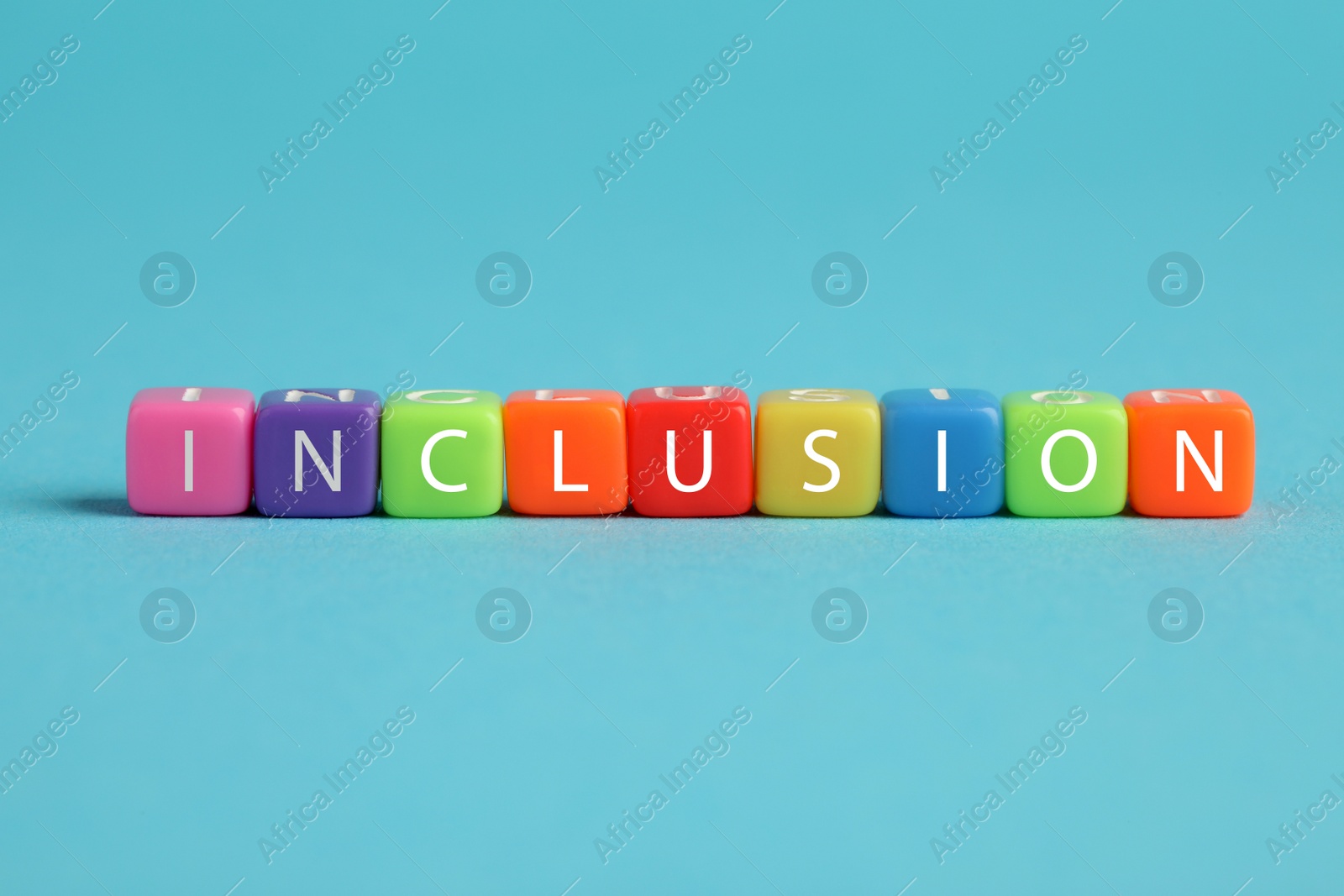 Photo of Colorful cubes with word Inclusion on light blue background