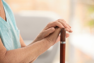 Elderly woman with cane in nursing home, closeup. Assisting senior generation