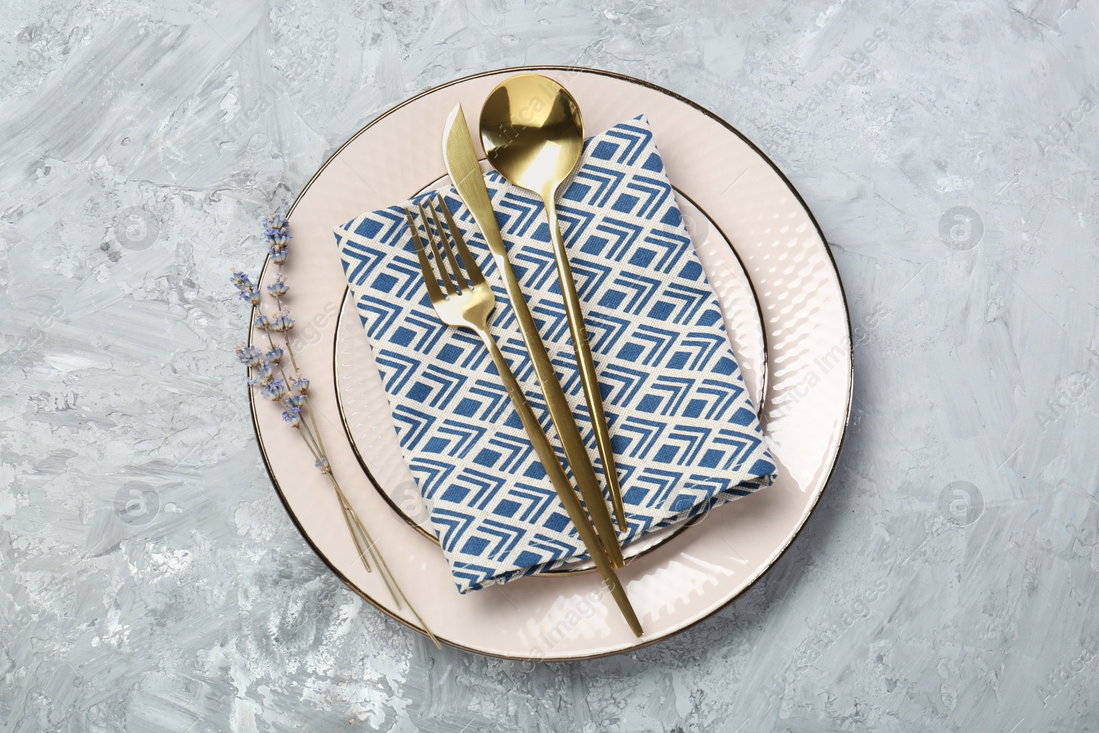 Photo of Clean plates, cutlery, napkin and lavender flowers on light grey textured table, top view