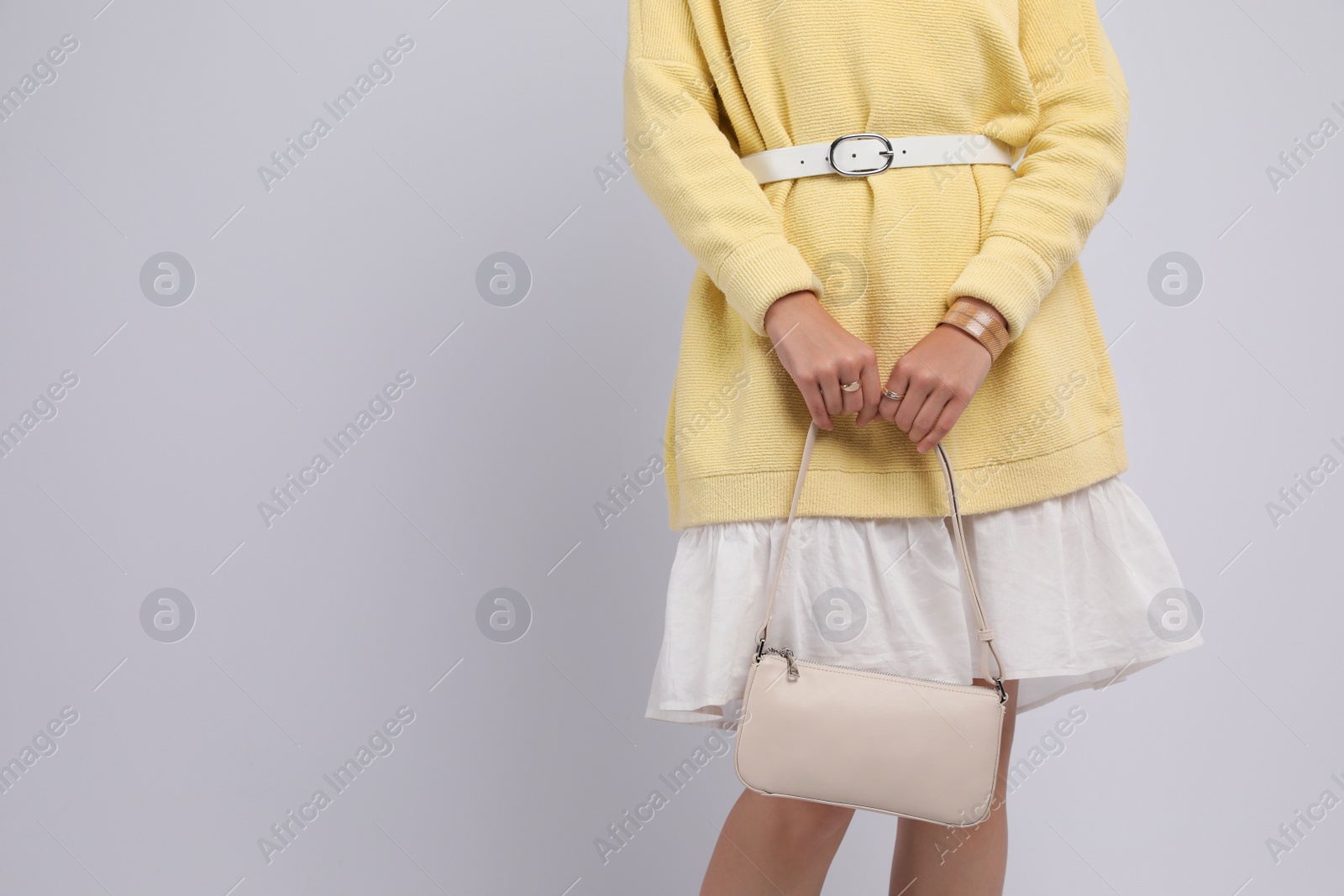 Photo of Fashionable woman with stylish bag on light background, closeup. Space for text