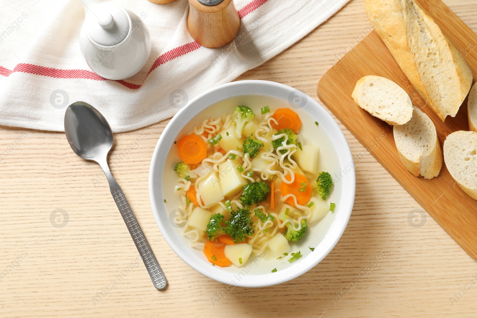 Photo of Bowl of fresh homemade vegetable soup served on wooden table, flat lay