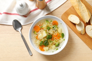 Photo of Bowl of fresh homemade vegetable soup served on wooden table, flat lay