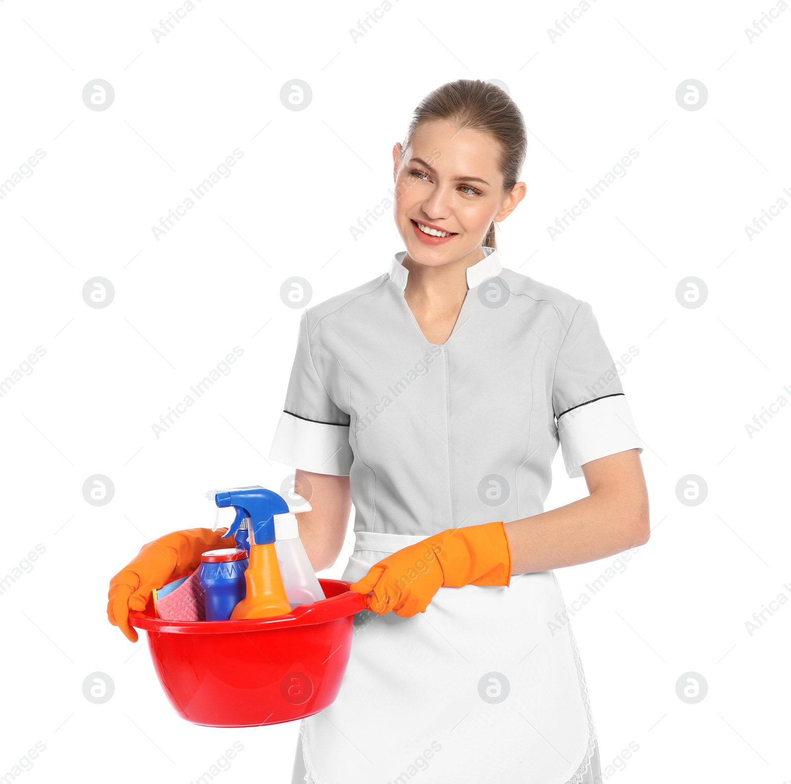 Photo of Young chambermaid holding basin with cleaning supplies on white background