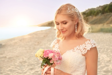 Happy bride holding wedding bouquet on beach