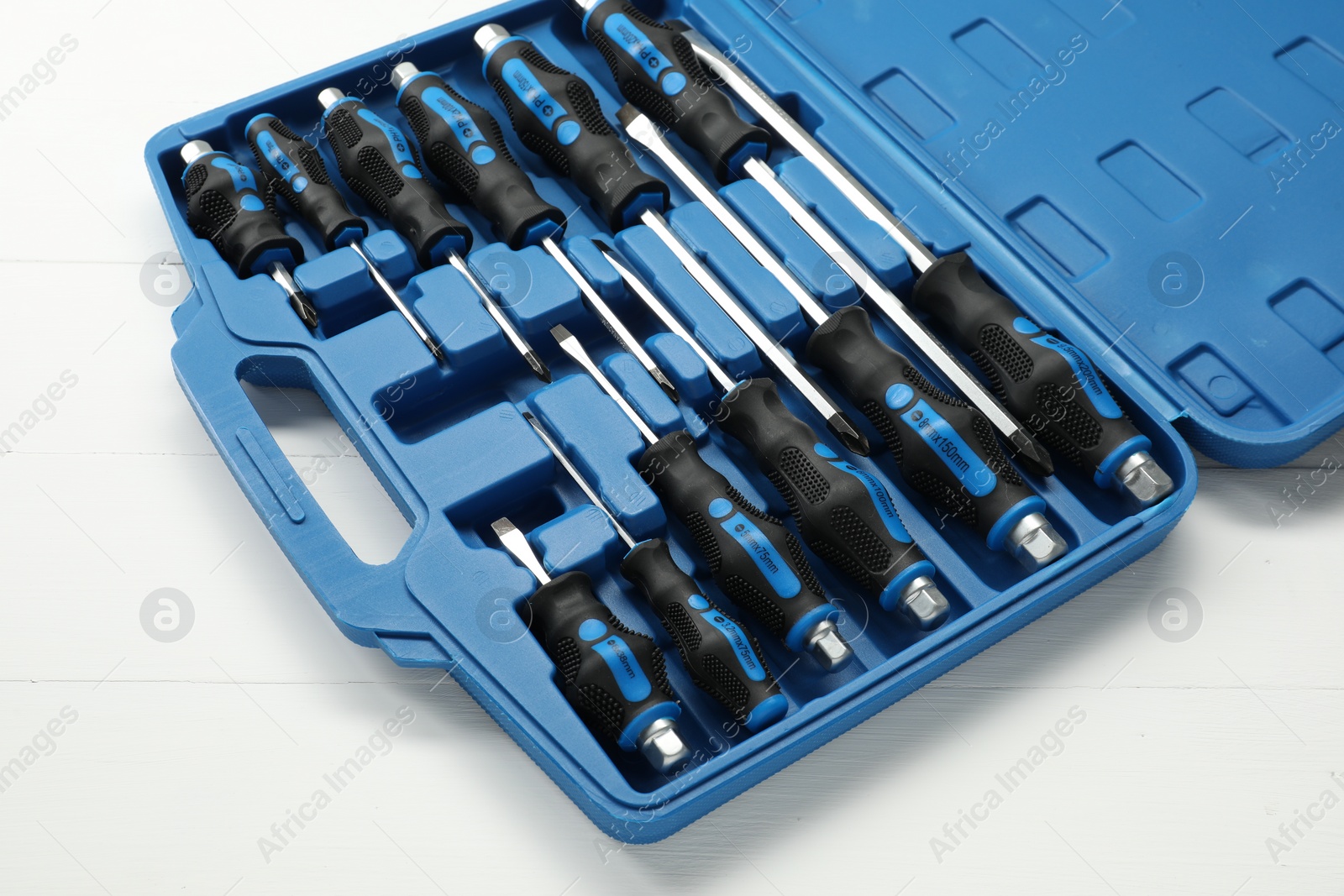 Photo of Set of screwdrivers in open toolbox on white wooden table, closeup