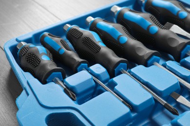 Set of screwdrivers in open toolbox on wooden table, closeup