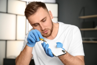 Technician repairing mobile phone in workshop, closeup